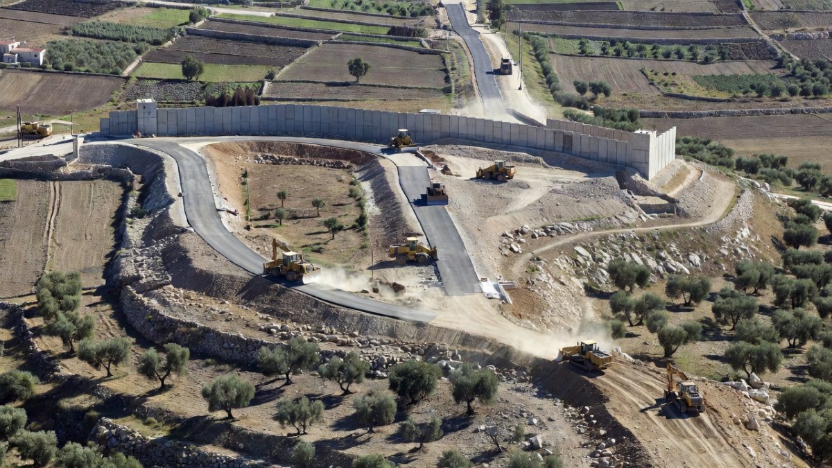 Aerial view of settlement construction on hilltops in the occupied West Bank, showing roads cutting through agricultural land