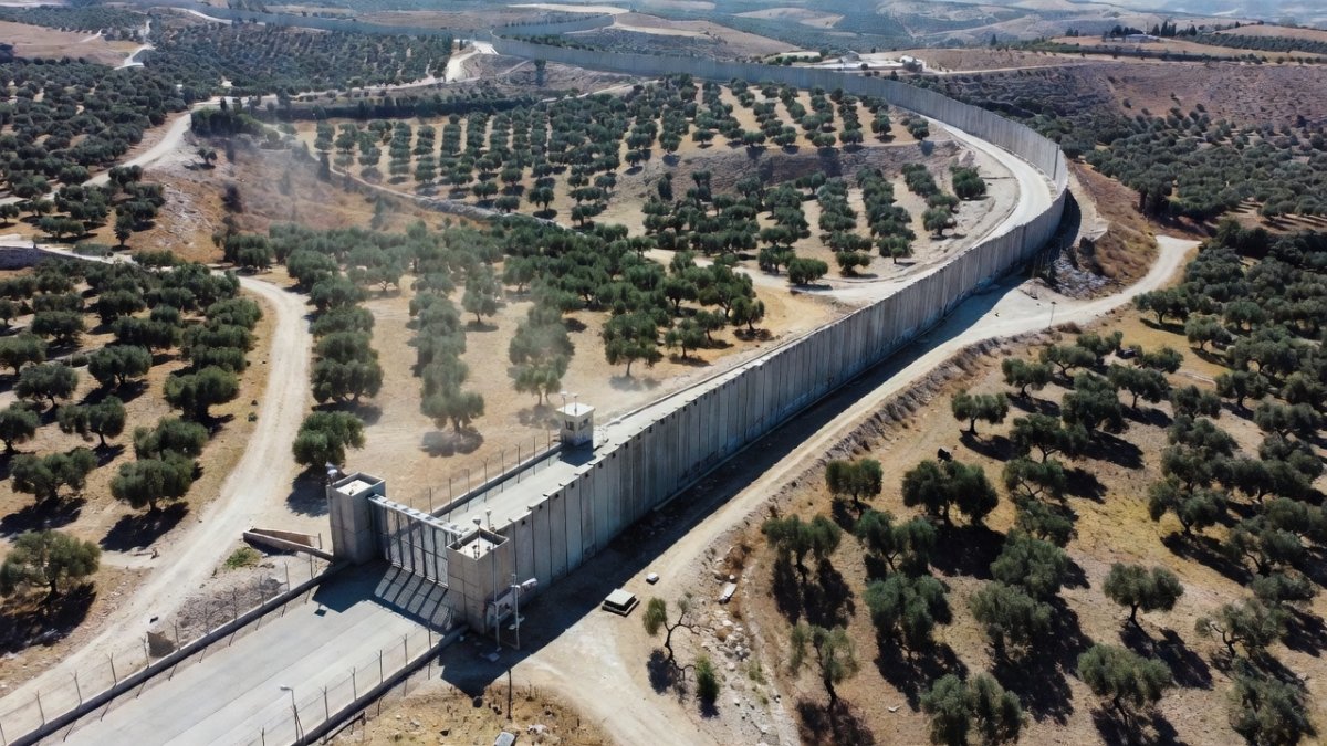 Aerial view of the West Bank separation barrier winding through hills and olive groves, a visual representation of the system Ta-Nehisi Coates witnessed