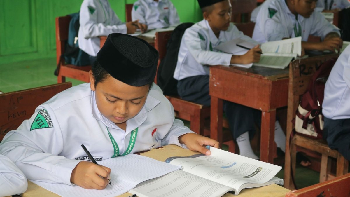 A student writing an exam paper at a desk