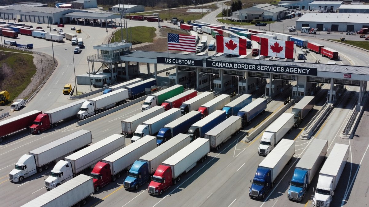US-Canada border crossing with commercial trucks, trade and tariffs dispute