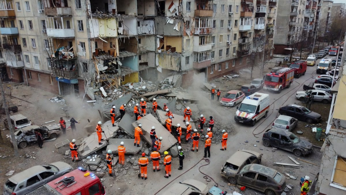 Rescue workers search through rubble of a collapsed apartment building in Kyiv's Darnitskyi district after Russian missile strike