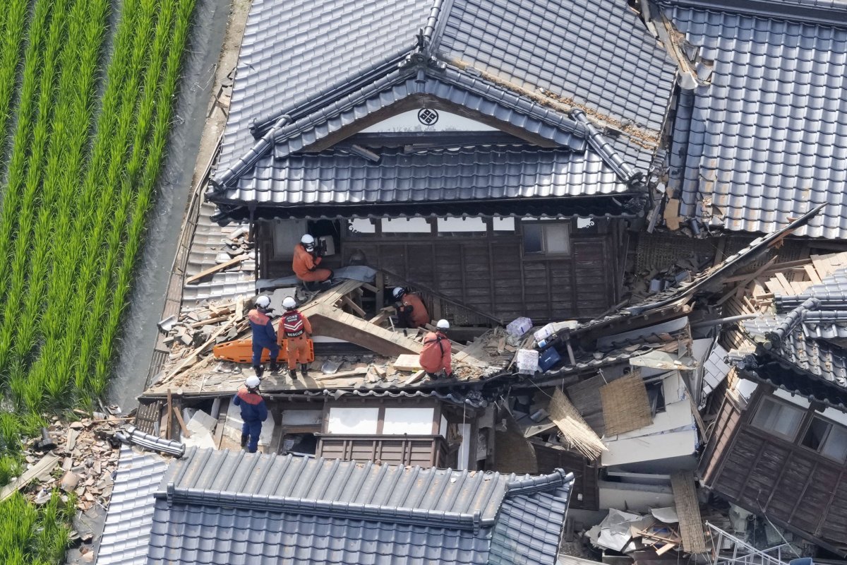 Rescue workers searching through rubble at a collapsed building in Kumamoto City