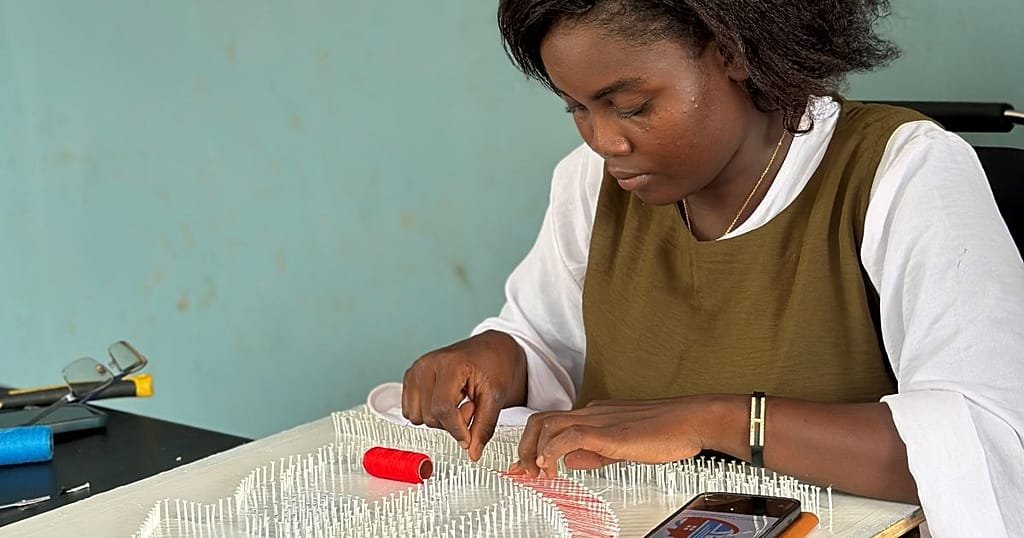 Close-up of thread art technique showing nails and colorful threads creating patterns