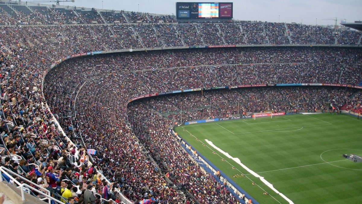 A packed football stadium pitch under lights