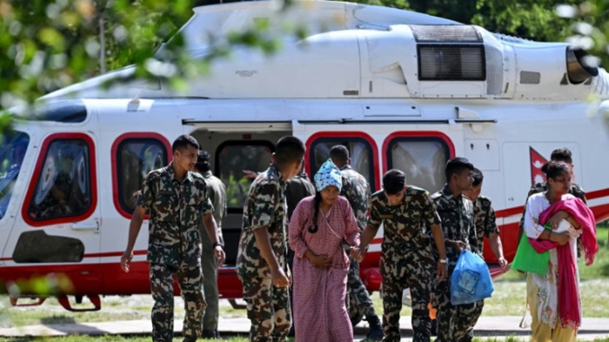 Army personnel escort a rescued woman at the Trishuli camp in Nuwakot district after the Nepal-Tibet border flash flood