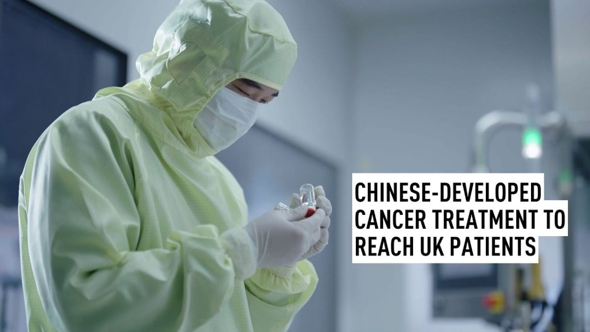 Pharmaceutical worker in a cleanroom laboratory inspecting a vial of cancer treatment