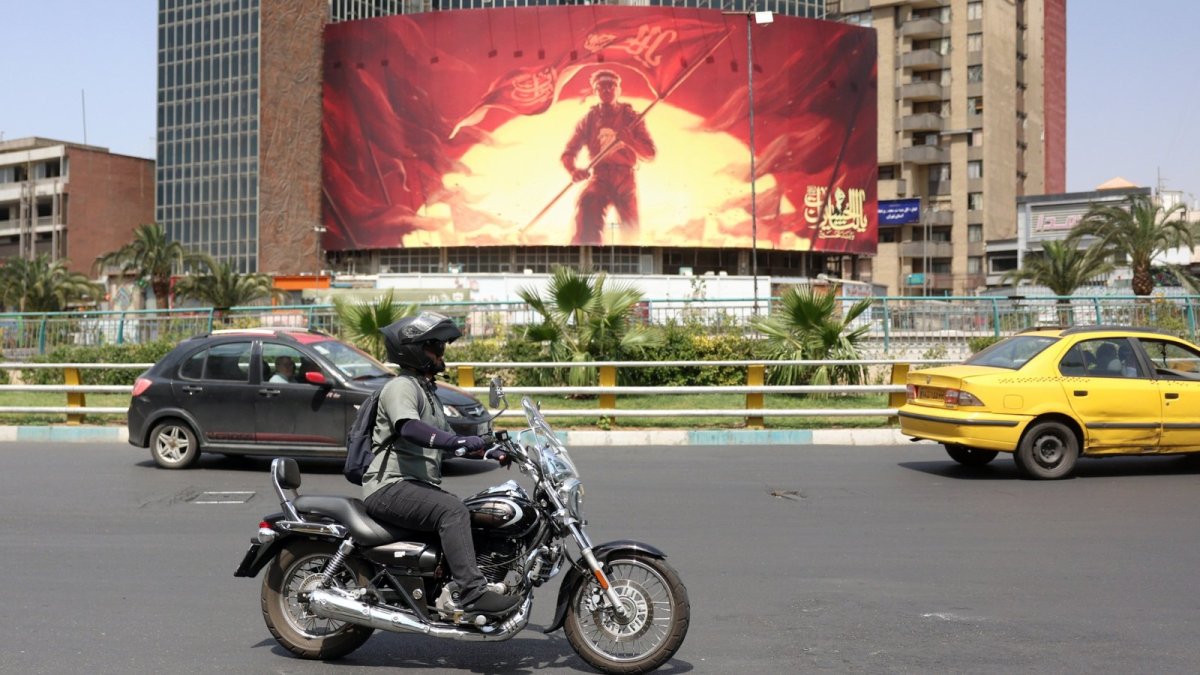 An Iranian rides a motorbike past a political billboard in Tehran, Iran, Aug. 17, 2026 (EPA Photo)