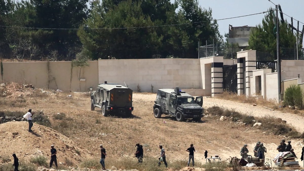Israeli settlers and soldiers outside besieged Palestinian homes in Qusra, south of Nablus