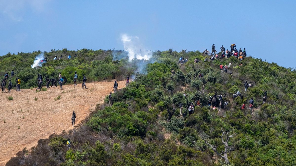 Moroccan security personnel disperse migrants with tear gas on hills near the Ceuta border
