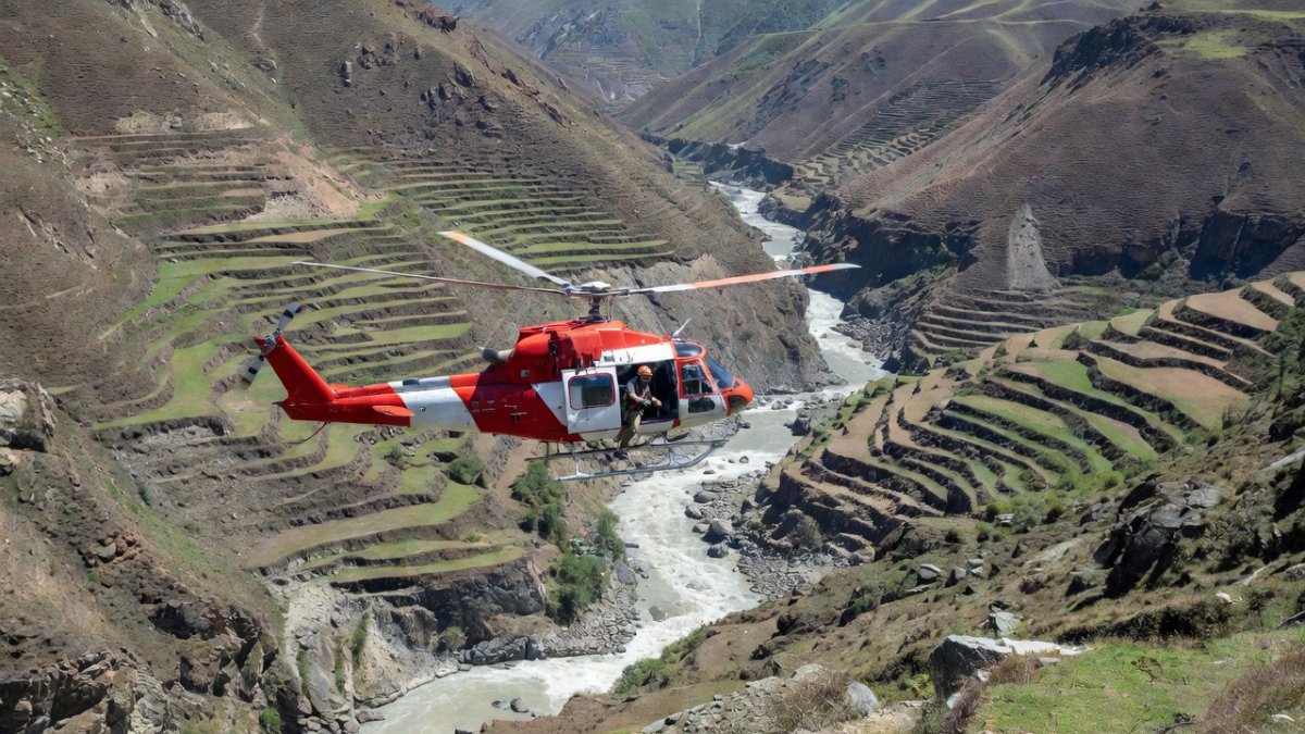 Rescue helicopter operating over a flood-hit Himalayan river valley in Nepal