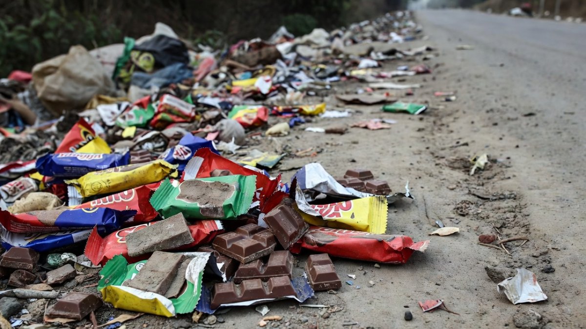 Chocolate confectionery and wrappers scattered on the ground near a dumping site