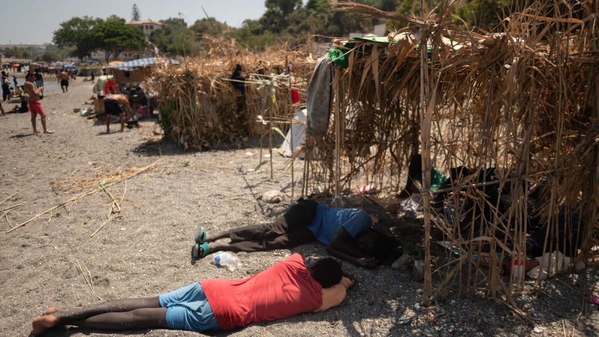 Migrants shelter from the sun on El Trampolin beach in Ceuta