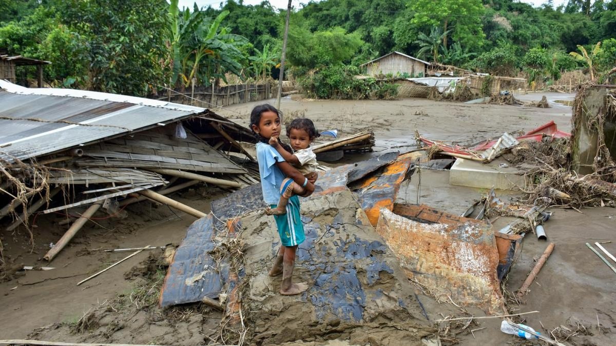 A girl stands on debris in the flood-ravaged Nepali Khuti area of Sivasagar, Assam