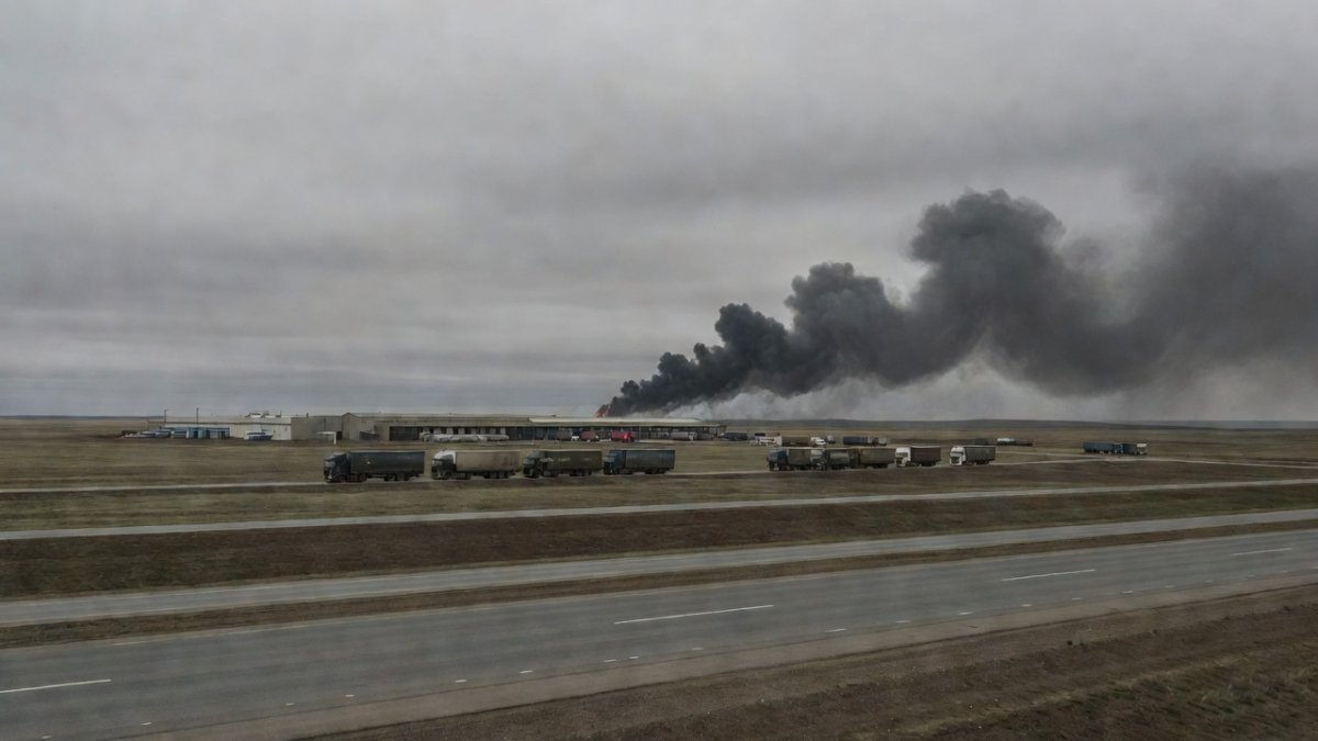 Wide shot of a motorway toward a Russian distribution warehouse complex with smoke on the horizon