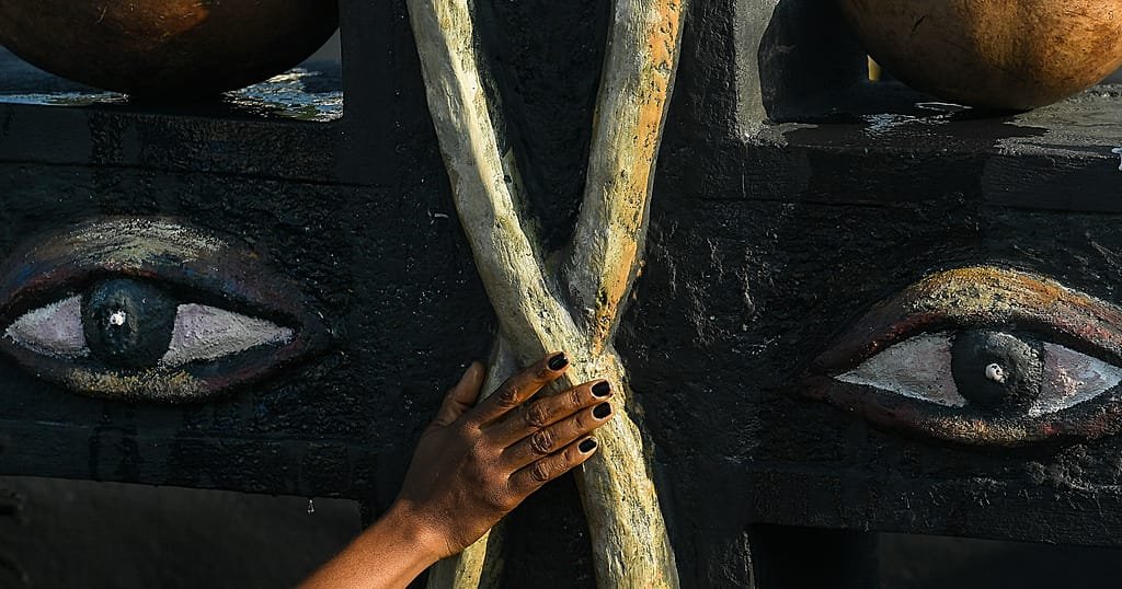 A person touches a monument to the Vodou spirits Baron Samedi and Gede at the National Cemetery in Port-au-Prince, Haiti
