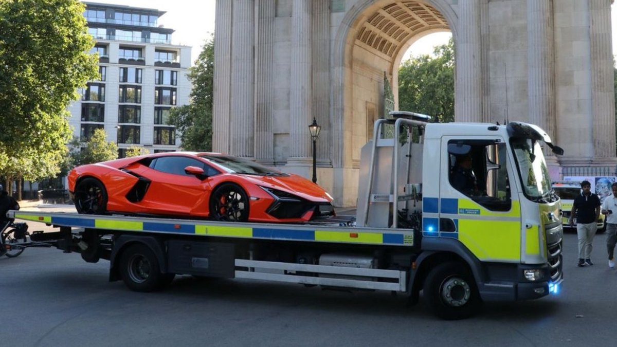 Metropolitan Police vehicle enforcement team officers inspect seized luxury cars at a police pound in London
