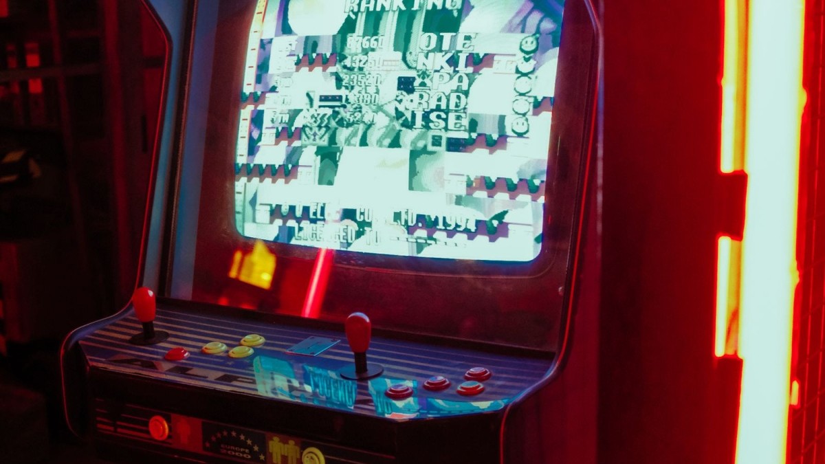 A retro arcade machine glowing with neon lights in a dark gaming room