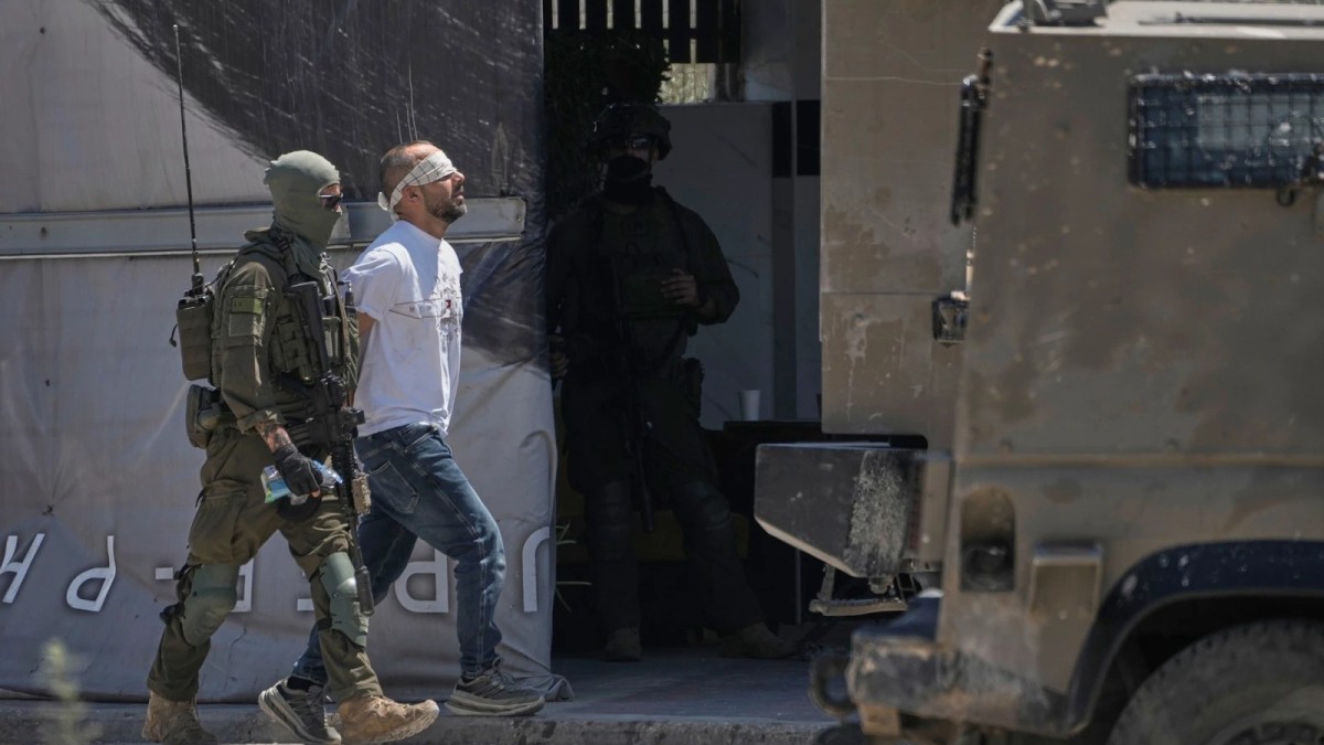 Israeli forces detain a Palestinian man during a raid in the Askar refugee camp near Nablus in the occupied West Bank