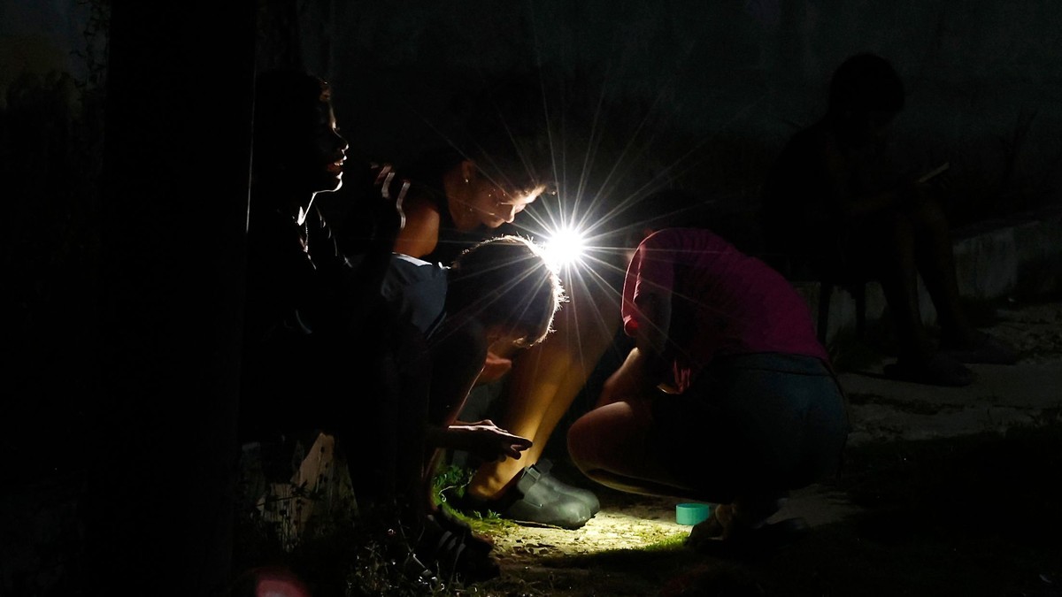 People light their path with a cell phone flashlight during the latest blackout to hit Cuba. Photo: Ernesto Mastrascusa/EPA