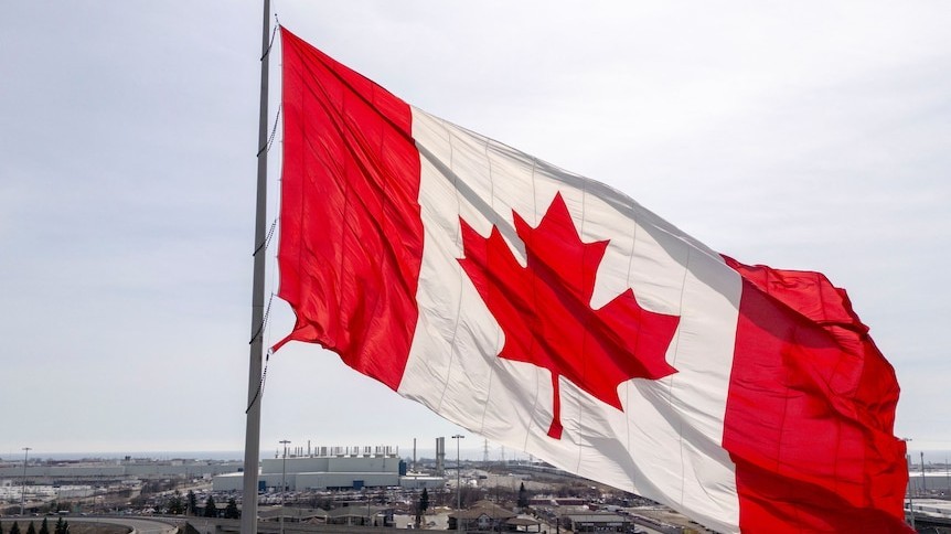 A Canadian flag flies over a city skyline amid deepening US-Canada trade tensions (Source: ABC News)
