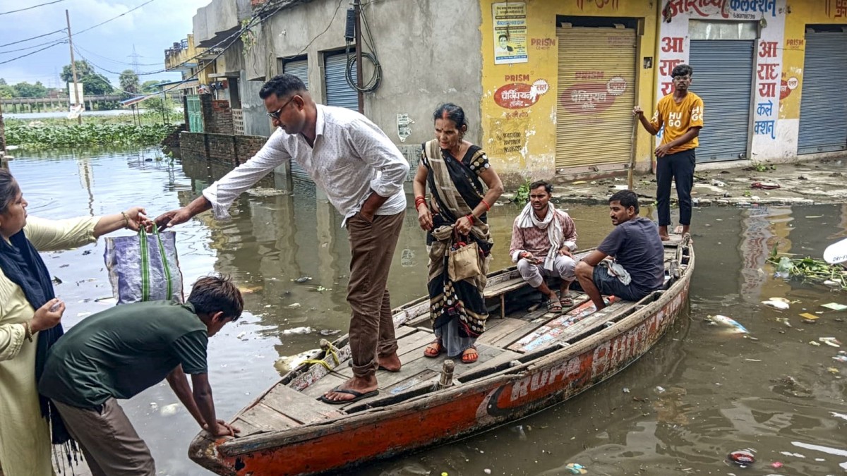 Residents row a boat through a flooded residential street in Varanasi along the swollen Varuna river
