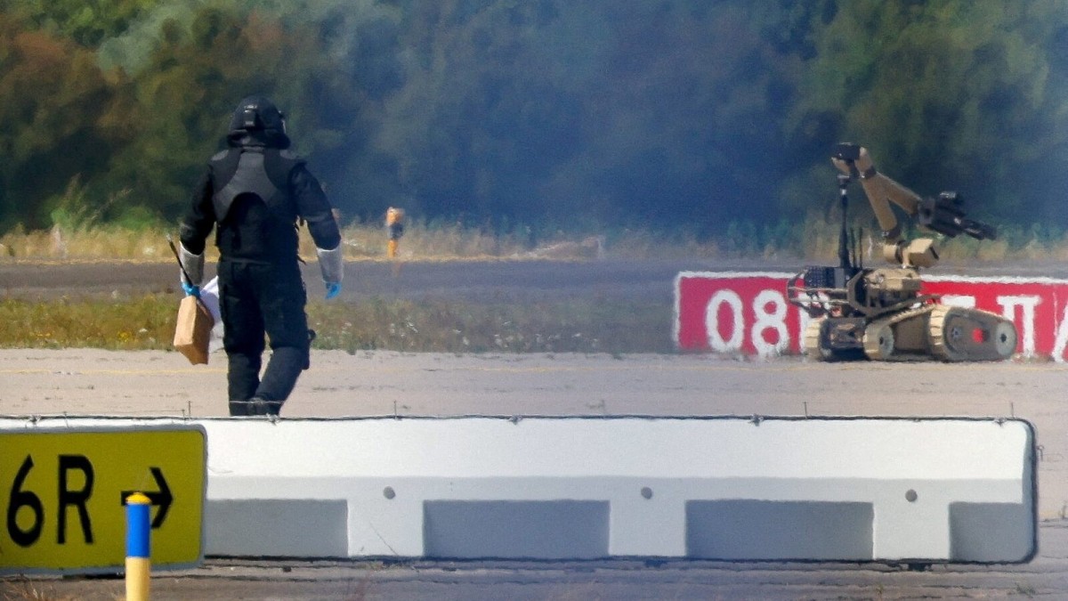 A police explosives-disposal officer and a tracked robot work the tarmac at Leipzig/Halle airport near a Ukrainian Antonov cargo aircraft
