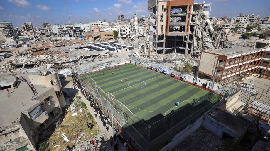 Young footballers play on a pitch amid the rubble of destroyed buildings at Palestine Stadium in Gaza City