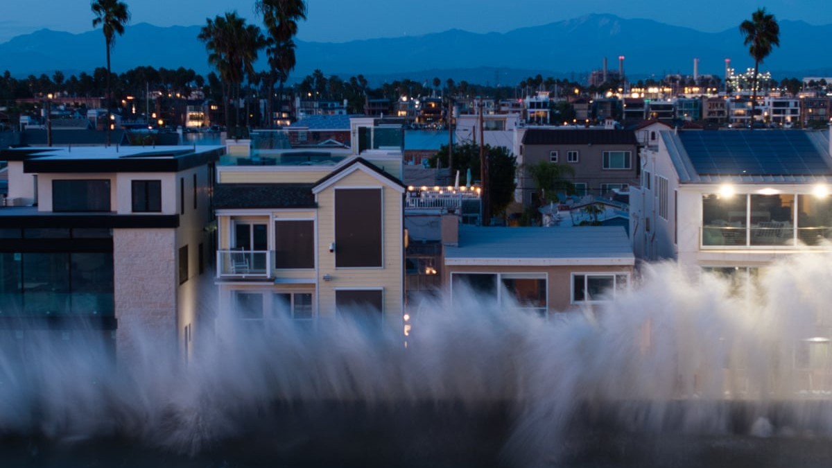 A large ocean wave breaks against a seawall in front of coastal homes at dusk in Long Beach, California, during a waning swell on September 8, 2026. Photo: Kelvin Kuo/Los Angeles Times via Getty Images