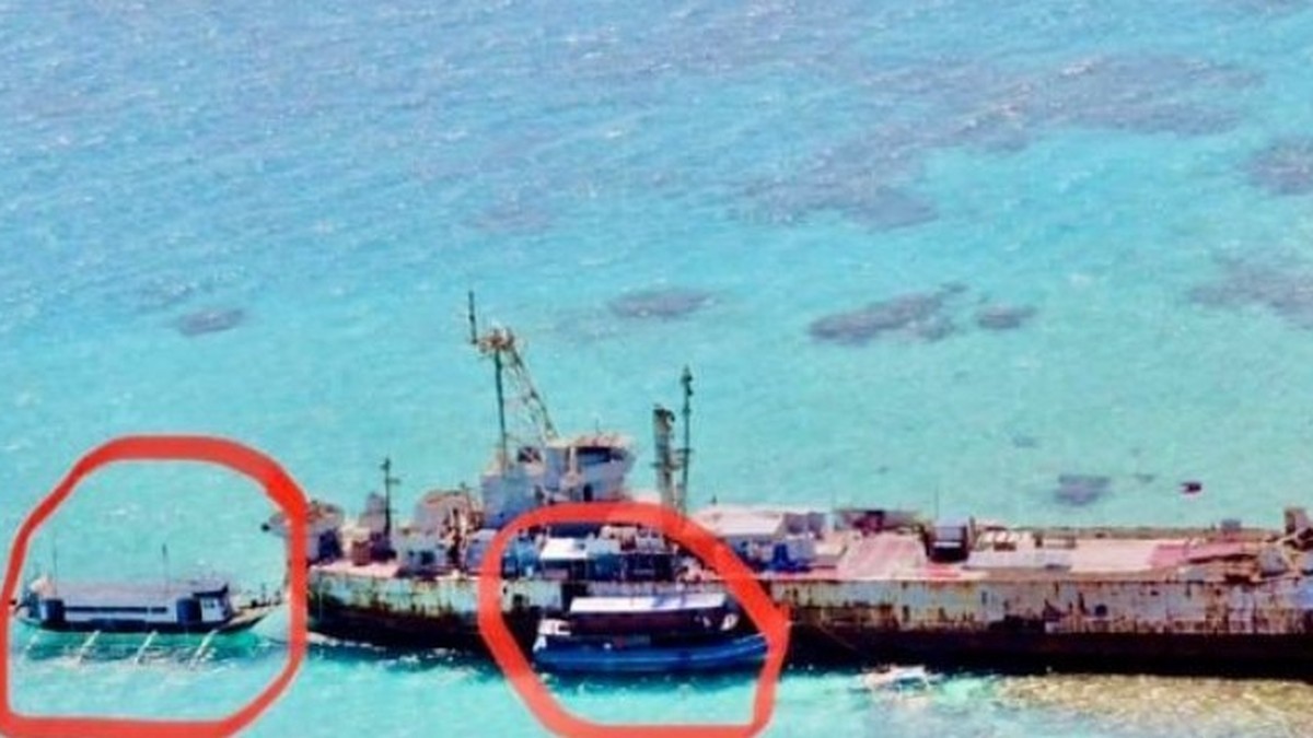 The BRP Sierra Madre grounded on Ayungin Shoal in the West Philippine Sea, seen from the air, with two small boats alongside the hull. Photo: AFP via the Philippine News Agency