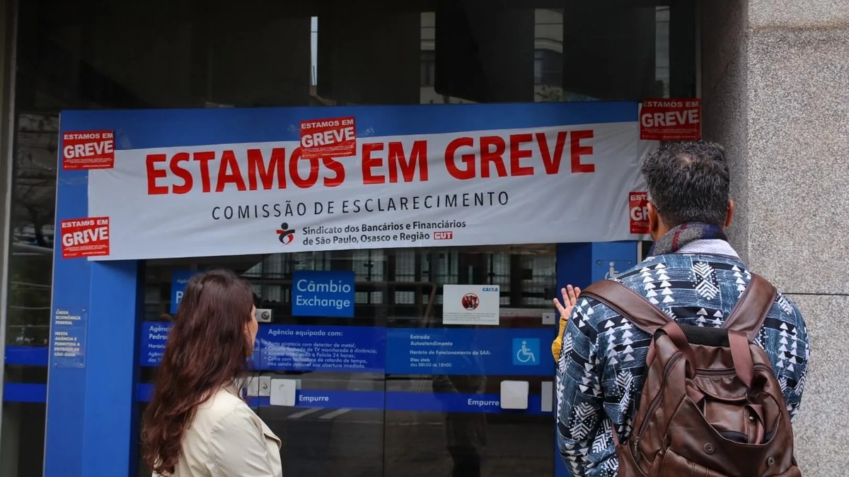 Bank workers outside a branch with an "Estamos em Greve" banner and union signage in Sao Paulo, Brazil. Photo: Brasil de Fato