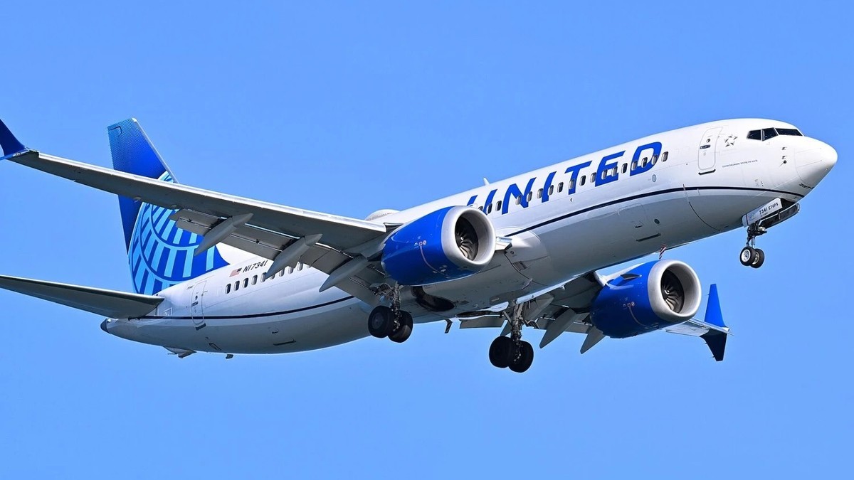 A United Airlines Boeing 737 in flight with its landing gear deployed, seen from below against a clear sky.