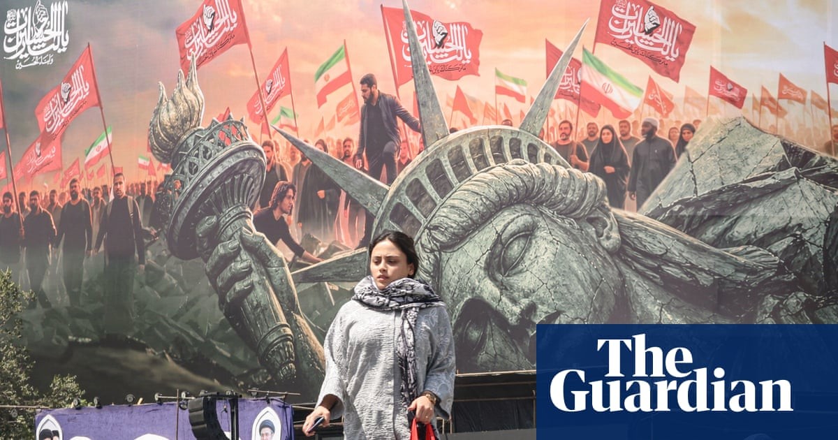 A woman crosses a street in Tehran in front of an anti-US billboard as the war between Iran and the United States continues