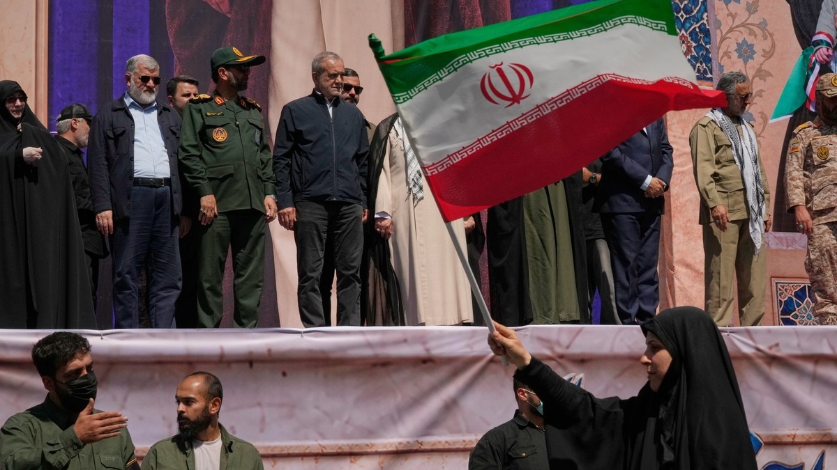 Iranian President Masoud Pezeshkian, center left, and other officials watch as a woman waves an Iranian flag during the Janfada parade in Tehran on Sept. 18, 2026. Photo: Vahid Salemi/AP