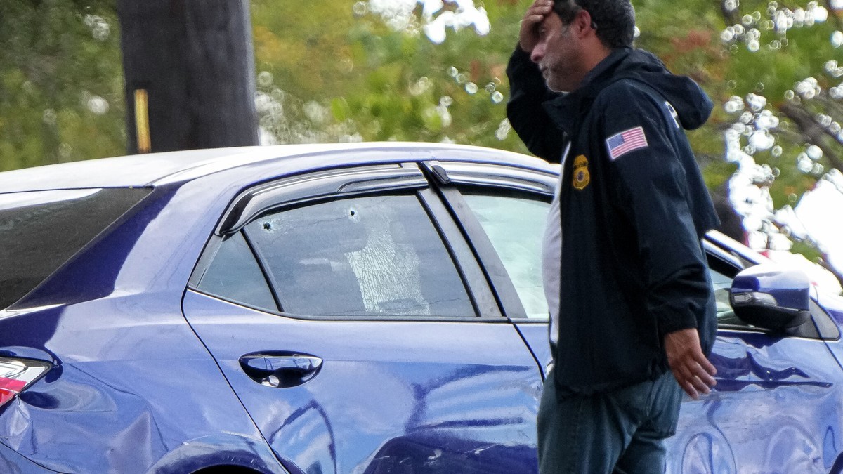 A federal agent walks past a vehicle with a damaged door and bullet holes in a broken window after an I.C.E. shooting at the intersection of Anderson Square and Research Boulevard on Sunday, Sep. 20, 2026 in North Austin. Photo: Aaron E. Martinez/Austin-American-Statesman
