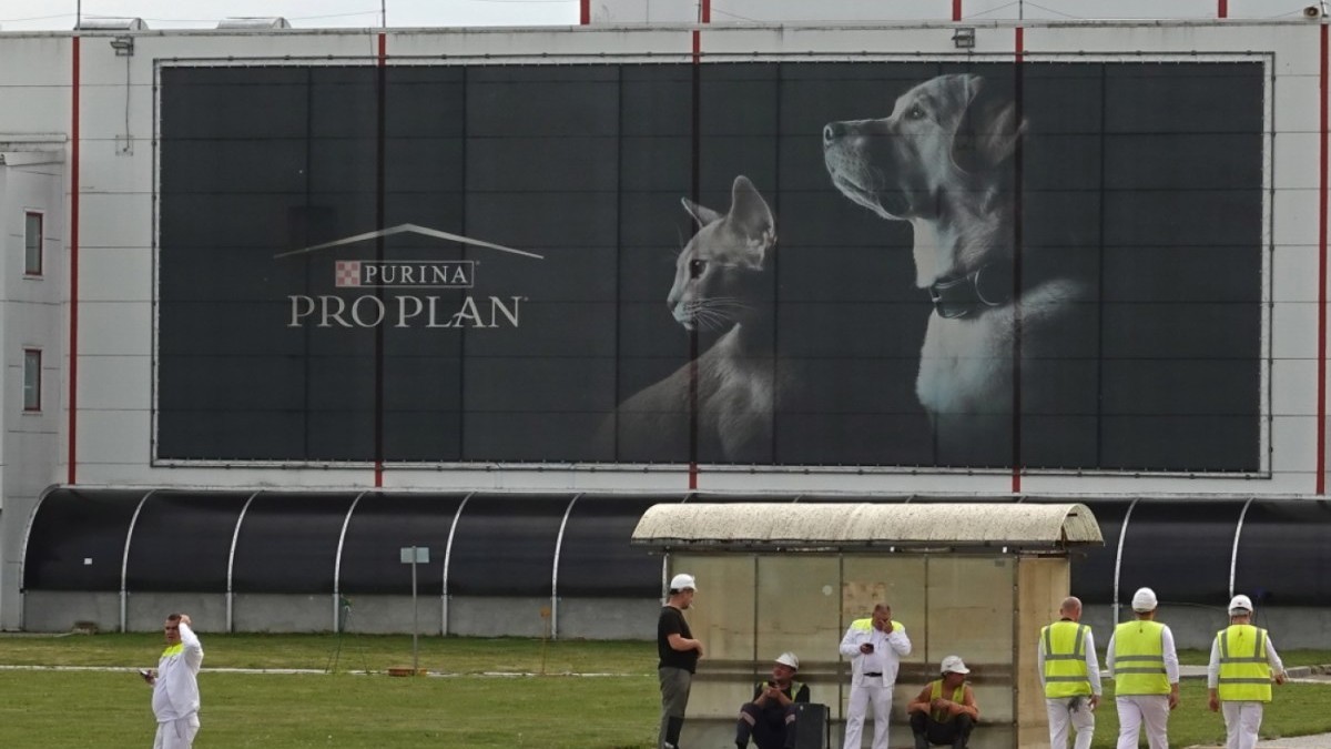 Workers outside a facility with a Purina Pro Plan advertisement in the foreground. Photo: Keystone-SDA via swissinfo.ch