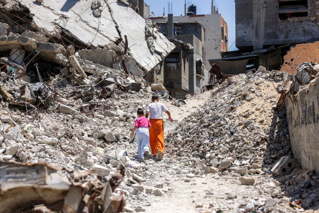 Two girls walk amid the rubble of Khan Younis in southern Gaza, 25 August 2026 (AFP)
