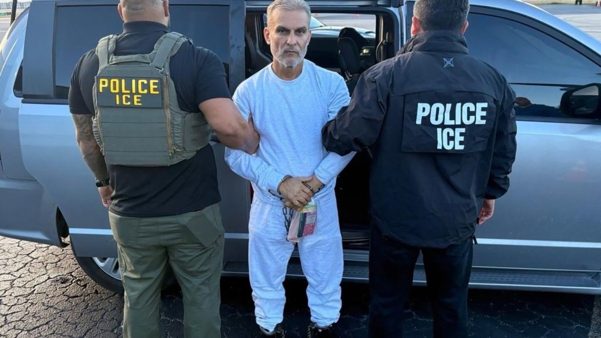 Former Ecuadorean Interior Minister Jose Serrano in handcuffs escorted by ICE officers