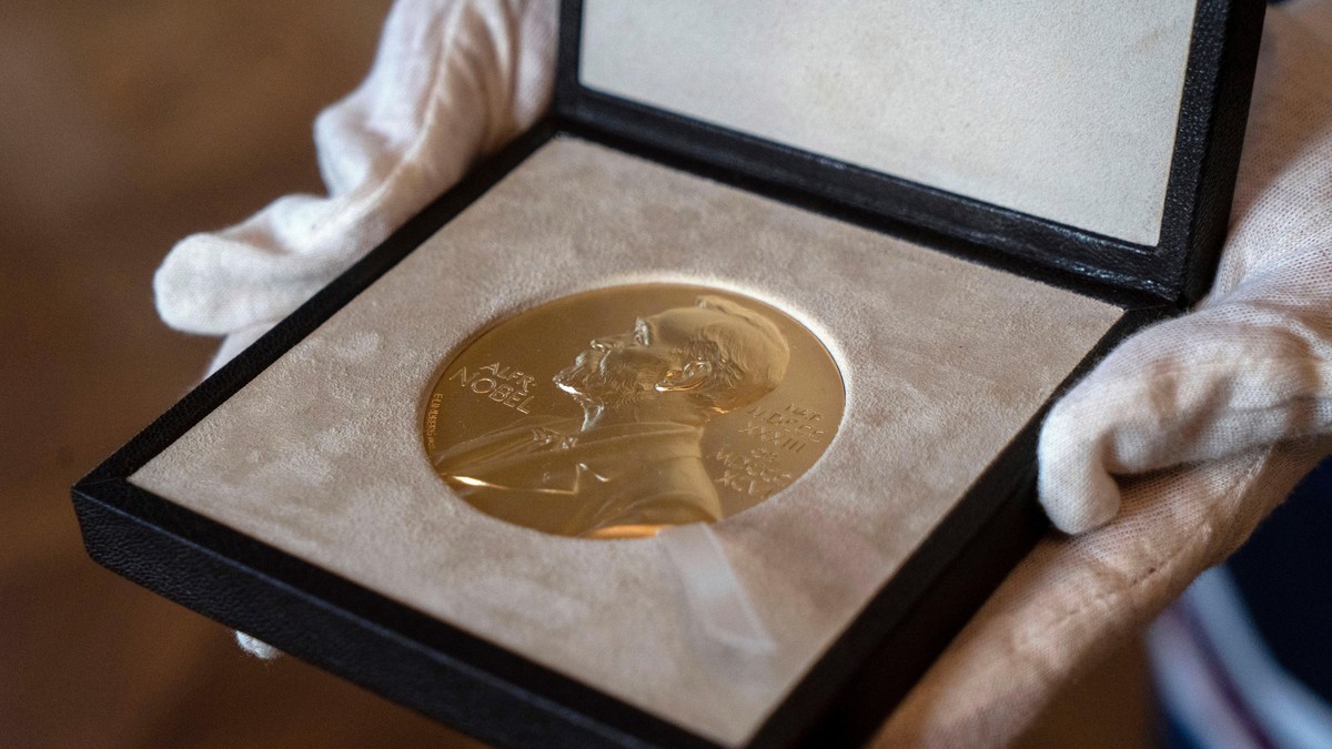 White-gloved hands hold an open presentation case containing a Nobel Prize medal. Photo: Associated Press