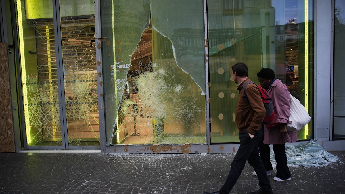 Two pedestrians walk past a shattered shop window in the Les Halles district of Paris. Photo: AP via ITV News