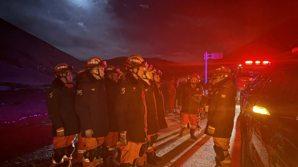 Rescue workers in orange uniforms and red helmets gather at night near damaged buildings in Nagqu, Tibet, after the magnitude 7.0 earthquake on 22 October 2026. Photo: CCTV via Reuters