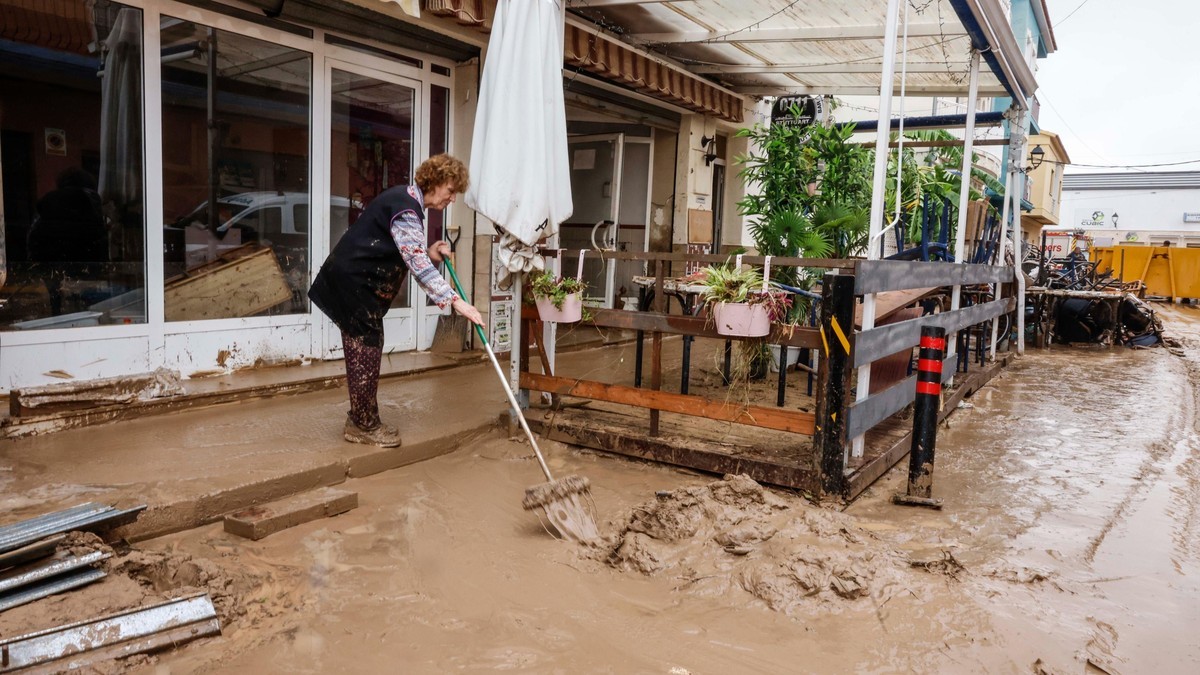 A resident clears mud from the doorway of a business in eastern Spain after Storm Adam. Photo: RTVE
