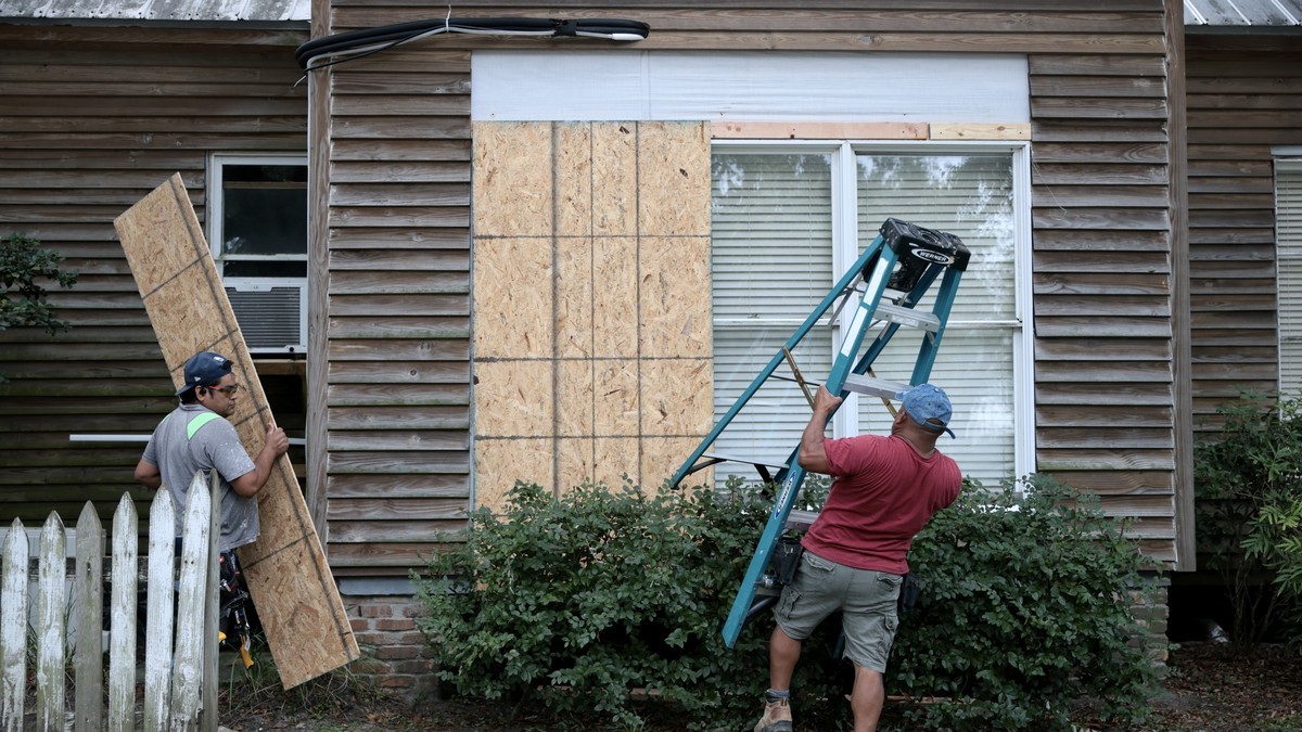 Aaron Chi and Wilner Garcia place plywood over the windows of a home in Pensacola, Florida, on 8 October 2026, ahead of Hurricane Isaias. Photo: Joe Raedle/Getty Images via Latin Times