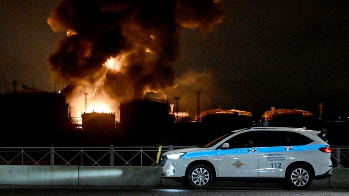 Smoke and flames rise from burning industrial buildings in St Petersburg on the night of 18 October 2026, with a Russian emergency service vehicle parked behind a barrier. Photo: BBC Russian