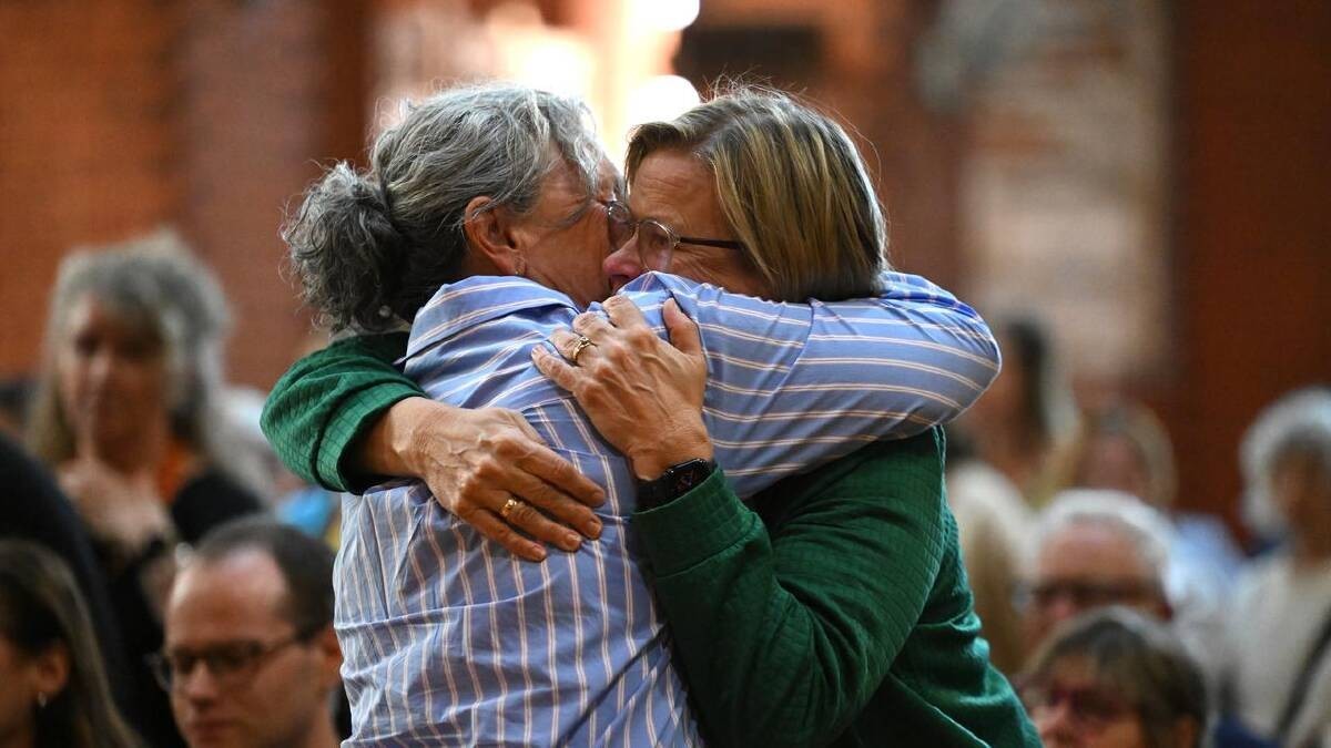 Residents embrace at a vigil for Helen Haines at Holy Trinity Anglican Cathedral in Wangaratta. Photo: James Ross/AAP