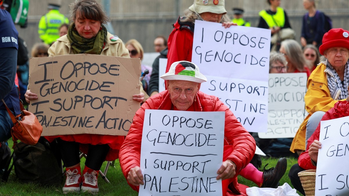 Demonstrators hold placards reading 'I oppose genocide, I support Palestine Action' at a protest outside the Labour Party conference in Liverpool. Photo: Temilade Adelaja/Reuters via Al Jazeera