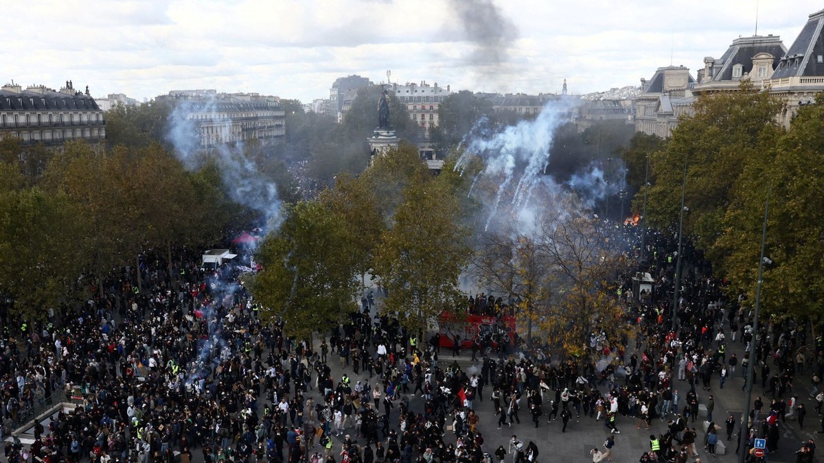 Demonstrators fill a Paris avenue as smoke rises during Saturday's nationwide protests against the cost of living. Photo: Reuters via CNN